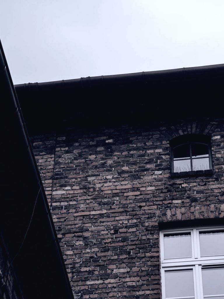 Backsteinfassade eines Bestandsgebäudes mit Dachrinne und alten Fensteröffnungen